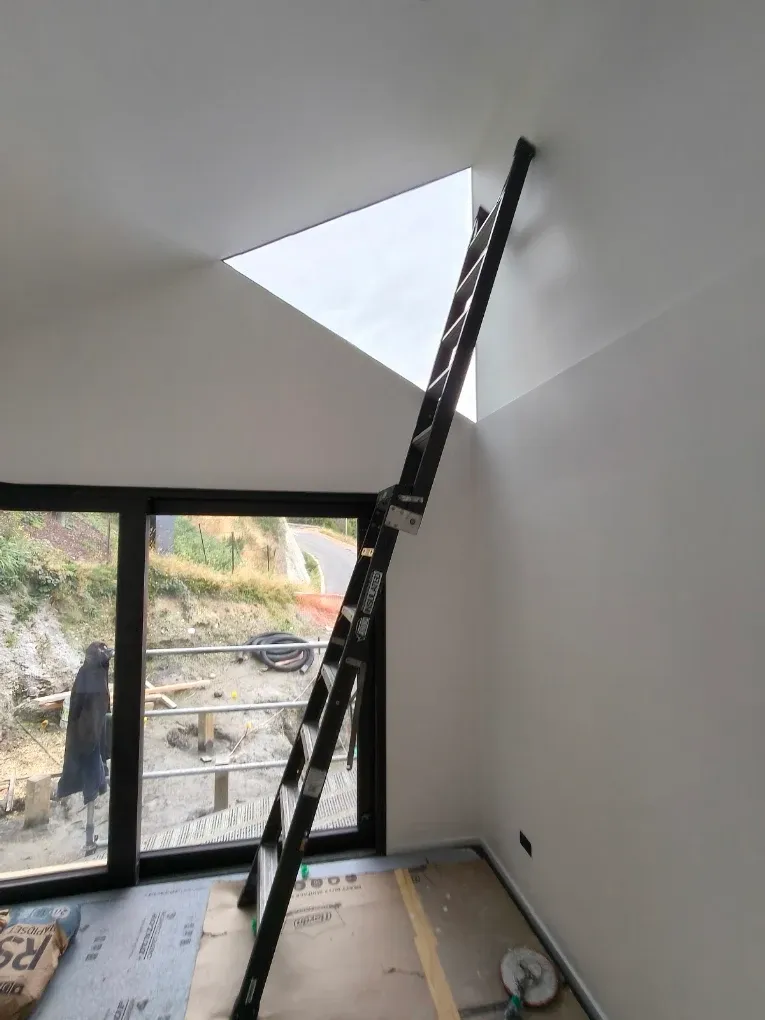 Ladder set against a vaulted ceiling mid-paint